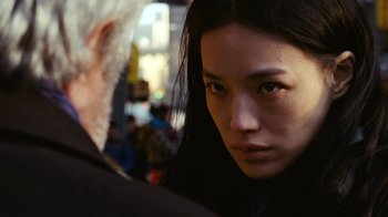 An asian woman with long black hair looking at an older man with grey hair