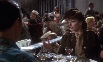 Movie still from “New York, New York” (1977), directed by Martin Scorsese – A woman sitting at a table in front of a group of people; Medium shot, Over the shoulder angle