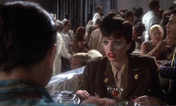 Movie still from “New York, New York” (1977), directed by Martin Scorsese – A woman in a military uniform sitting at a table with a glass of red wine; Medium shot, Over the shoulder angle