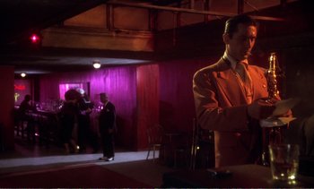 Movie still from “New York, New York” (1977), directed by Martin Scorsese – A man standing in a room with people in the background; Medium shot, Low angle