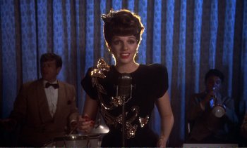 Movie still from “New York, New York” (1977), directed by Martin Scorsese – A woman in a black dress is singing into a microphone; Medium shot, Low angle