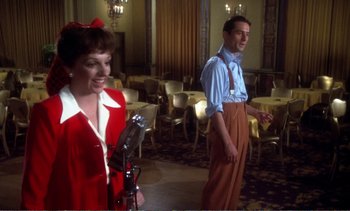 Movie still from “New York, New York” (1977), directed by Martin Scorsese – A man and a woman singing into a microphone; Medium shot, Over the shoulder angle