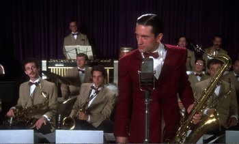 Movie still from “New York, New York” (1977), directed by Martin Scorsese – A man in a red jacket is on a stage with a saxophone; Medium shot, Low angle