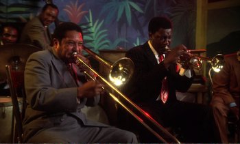 Movie still from “New York, New York” (1977), directed by Martin Scorsese – A group of men playing musical instruments in a room; Medium shot, Low angle