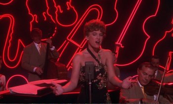 Movie still from “New York, New York” (1977), directed by Martin Scorsese – A woman singing in front of a microphone in front of a neon sign; Medium shot, Over the shoulder angle
