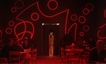 Movie still from “New York, New York” (1977), directed by Martin Scorsese – A woman standing in a doorway in front of a wall of red lights; Wide shot, Low angle