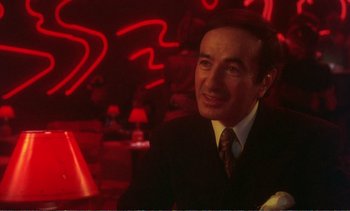 Movie still from “New York, New York” (1977), directed by Martin Scorsese – A man in a suit and tie sitting in front of a neon sign; Close Up shot, Over the shoulder angle