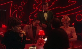 Movie still from “New York, New York” (1977), directed by Martin Scorsese – A group of people sitting at a table in front of a lamp; Wide shot, Over the shoulder angle