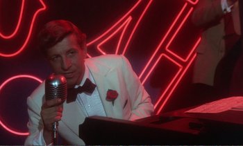 Movie still from “New York, New York” (1977), directed by Martin Scorsese – A man in a white suit holding a silver microphone; Medium shot, Over the shoulder angle