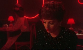 Movie still from “New York, New York” (1977), directed by Martin Scorsese – A woman in a black dress in front of a red light; Medium shot, Over the shoulder angle