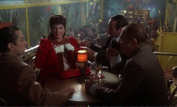 Movie still from “New York, New York” (1977), directed by Martin Scorsese – A group of people sitting at a table with drinks; Medium shot, Over the shoulder angle