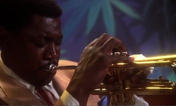 Movie still from “New York, New York” (1977), directed by Martin Scorsese – A man playing a trumpet in front of a blue and green background; Extreme Close Up shot, Low angle