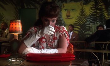 Movie still from “New York, New York” (1977), directed by Martin Scorsese – A woman in a red dress and white gloves is sitting in front of a painting; Medium shot, Over the shoulder angle