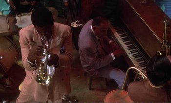 Movie still from “New York, New York” (1977), directed by Martin Scorsese – Two men in suits playing musical instruments in a room; Medium shot, High angle