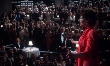 Movie still from “New York, New York” (1977), directed by Martin Scorsese – A woman in a red dress speaking to a crowd of onlookers; Wide shot, High angle