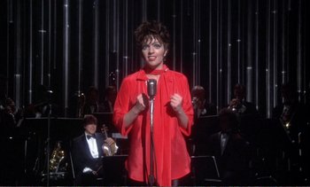 Movie still from “New York, New York” (1977), directed by Martin Scorsese – A woman in a red shirt is singing into a microphone; Medium shot, High angle