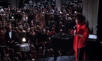 Movie still from “New York, New York” (1977), directed by Martin Scorsese – A woman in a red shirt is speaking to a crowd; Extreme Wide shot, High angle