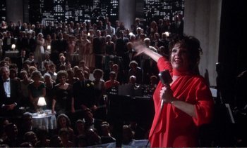 Movie still from “New York, New York” (1977), directed by Martin Scorsese – A woman in a red dress is holding a microphone; Wide shot, High angle