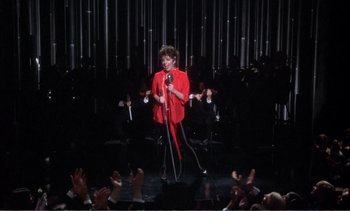 Movie still from “New York, New York” (1977), directed by Martin Scorsese – A woman in a red shirt is singing into a microphone; Extreme Wide shot, High angle