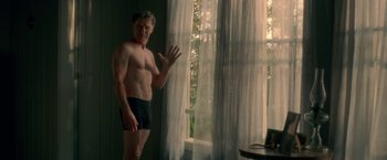 Movie still from “Gerald's Game” (2017), directed by Mike Flanagan – A shirtless man standing in front of a window; Medium shot, Low angle