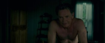 Movie still from “Gerald's Game” (2017), directed by Mike Flanagan – A shirtless man poses for the camera in a dark room; Close Up shot, High angle