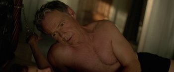 Movie still from “Gerald's Game” (2017), directed by Mike Flanagan – An older man with no shirt is posing for the camera; Close Up shot, High angle