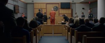 Movie still from “Gerald's Game” (2017), directed by Mike Flanagan – A man in an orange jumpsuit stands in a courtroom; Wide shot, Low angle