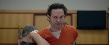 Movie still from “Gerald's Game” (2017), directed by Mike Flanagan – A man in an orange shirt is sitting in a room; Close Up shot, Over the shoulder angle