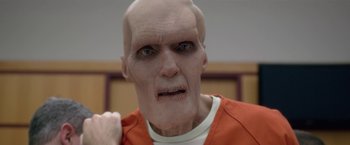 Movie still from “Gerald's Game” (2017), directed by Mike Flanagan – A man with a bald head wearing an orange shirt; Extreme Close Up shot, Low angle