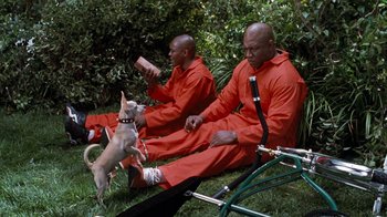 Movie still from “Next Friday” (2000), directed by Steve Carr – A couple of men sitting next to each other on a field; Wide shot, High angle