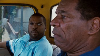 Movie still from “Next Friday” (2000), directed by Steve Carr – Two men sitting on a bus looking at the camera; Close Up shot, Over the shoulder angle
