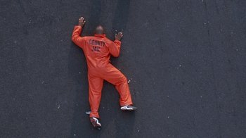 Movie still from “Next Friday” (2000), directed by Steve Carr – A man in orange jail suit laying on the ground; Extreme Wide shot, Overhead angle