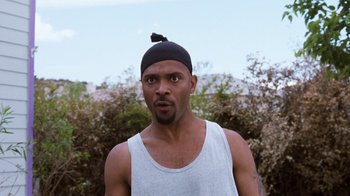 Movie still from “Next Friday” (2000), directed by Steve Carr – A person wearing a tank top and a hat; Close Up shot, Over the shoulder angle