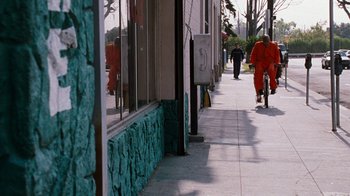 Movie still from “Next Friday” (2000), directed by Steve Carr – A man riding a bike down a sidewalk next to a building; Wide shot, High angle
