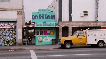 Movie still from “Next Friday” (2000), directed by Steve Carr – A truck parked on the side of the road next to a restaurant; Wide shot, High angle
