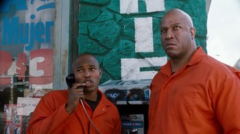 Movie still from “Next Friday” (2000), directed by Steve Carr – A couple of men standing next to each other near a pay phone; Medium shot, Low angle