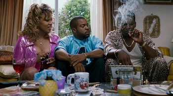 Movie still from “Next Friday” (2000), directed by Steve Carr – A group of people sitting around a table smoking; Medium shot, Low angle
