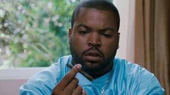 Movie still from “Next Friday” (2000), directed by Steve Carr – A person holding a cigar; Close Up shot, Over the shoulder angle