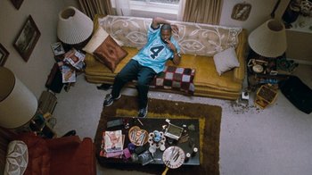 Movie still from “Next Friday” (2000), directed by Steve Carr – A man laying on a couch in a living room; Wide shot, Overhead angle