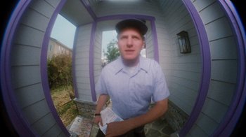 Movie still from “Next Friday” (2000), directed by Steve Carr – A man sitting on a porch holding a piece of paper; Medium shot, Low angle