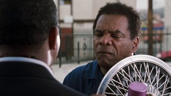 Movie still from “Next Friday” (2000), directed by Steve Carr – An older man holding a bicycle wheel in front of a younger man; Close Up shot, Over the shoulder angle