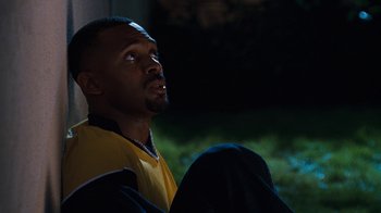 Movie still from “Next Friday” (2000), directed by Steve Carr – A man sitting on the ground in the dark; Medium shot, High angle