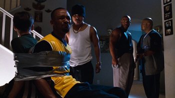 Movie still from “Next Friday” (2000), directed by Steve Carr – A group of men standing in a living room; Wide shot, High angle