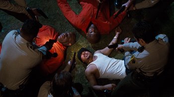Movie still from “Next Friday” (2000), directed by Steve Carr – A group of people laying on the ground holding guns; Medium shot, Overhead angle