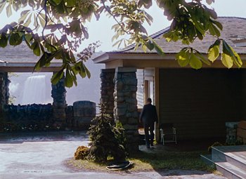 Movie still from “Niagara” (1953), directed by Henry Hathaway – An older man standing in front of a house; Extreme Wide shot, Over the shoulder angle