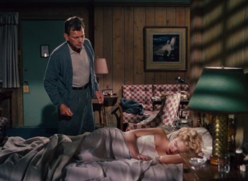 Movie still from “Niagara” (1953), directed by Henry Hathaway – A man standing next to a woman laying in a bed; Wide shot, High angle
