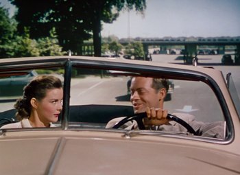 Movie still from “Niagara” (1953), directed by Henry Hathaway – A man and a woman sitting in the driver's seat of a car; Medium shot, Over the shoulder angle
