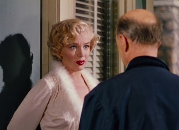 Movie still from “Niagara” (1953), directed by Henry Hathaway – A woman with blonde hair wearing a white dress and a man with a bald head; Medium shot, Over the shoulder angle