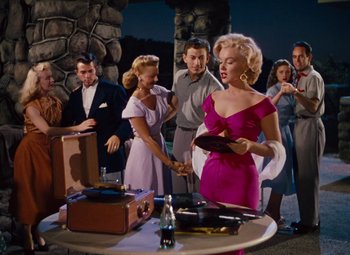 Movie still from “Niagara” (1953), directed by Henry Hathaway – A group of people standing around a table with a tray of food; Medium shot, Low angle