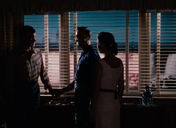 Movie still from “Niagara” (1953), directed by Henry Hathaway – Two men and a woman standing in front of a window; Wide shot, Over the shoulder angle